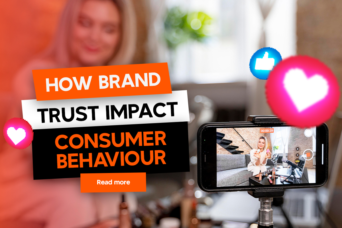 A person streaming content on a smartphone. The screen displays "How Brand Trust Impact Consumer Behaviour" with bright graphics and icons around, including hearts and thumbs-up symbols. A button reads "Read more.