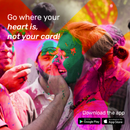 A group of people celebrating with colorful powder. Text reads, "Go where your heart is, not your card! Download the app." Google Play and App Store icons are visible.