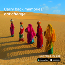 Five women in colorful traditional attire walk across a desert carrying pots on their heads. The text says, "Carry back memories, not change." App store icons are displayed at the bottom.