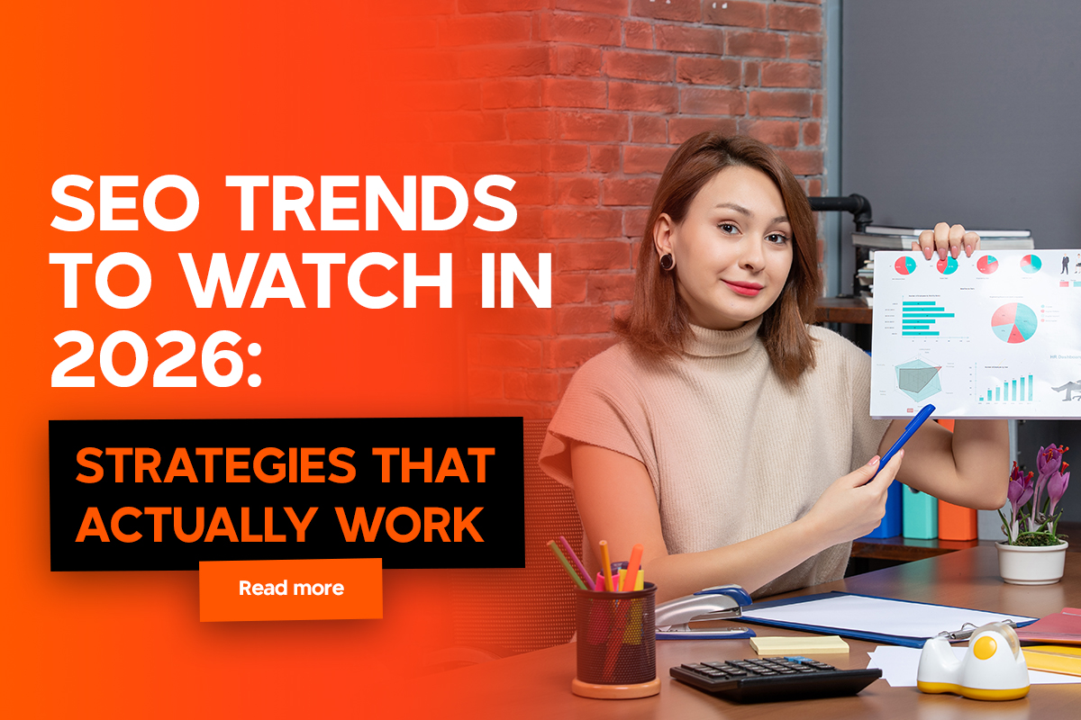 A woman in a beige top sits at a desk, pointing to colorful charts on a paper. The setting includes a brick wall, books, and a model ship, creating a professional atmosphere.